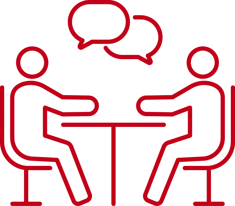 Dieses rote Symbol zeigt zwei Personen, die an einem Tisch sitzen und sich unterhalten.